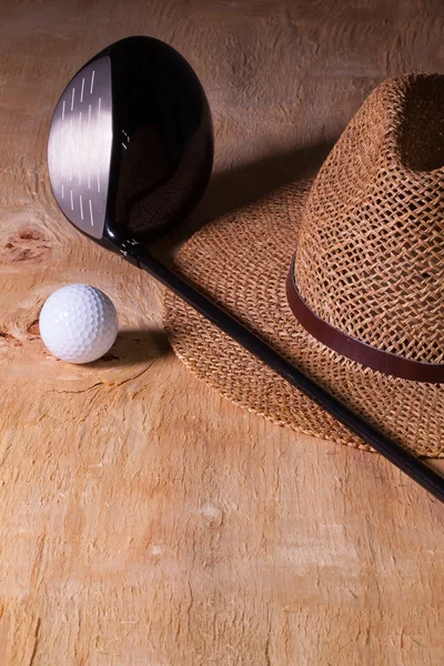 Siesta - straw hat and golf driver on a wooden desk