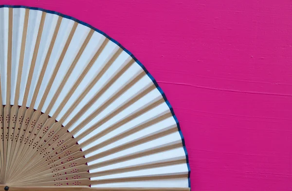 Typical Japanese hand fan made on the wooden pink desl