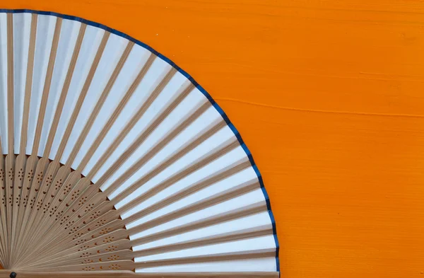 Typical Japanese hand fan made on the wooden orange desk