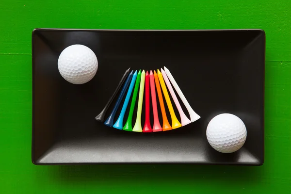 Black ceramic dishes with golf balls and wooden tees