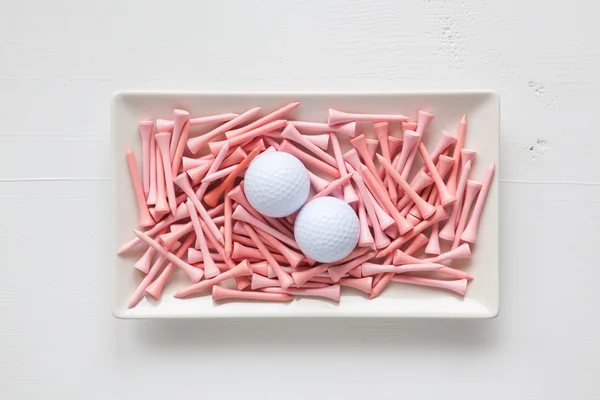 White ceramic dishes with golf balls and wooden tees