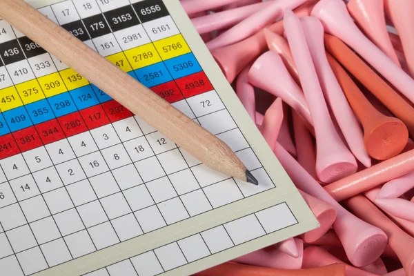 Wooden pencil and golf score card  lying  on a golf tees