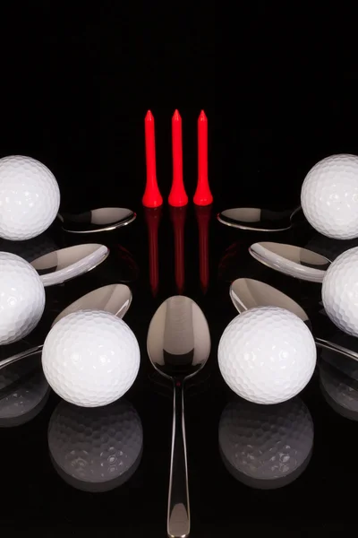 Teaspoons and golf equipments on the black glass table