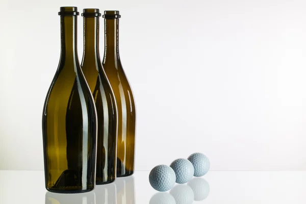 Empty wine bottles and golf balls on a glass desk