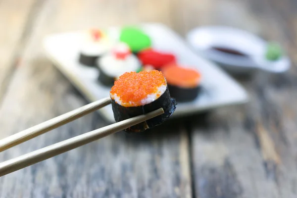 Sushi roll with chopsticks on old wood background