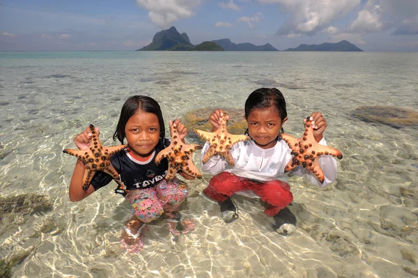 SEMPORNA, MALAYSIA- MARCH 6, 2015 : Unidentified bajau girls catch starfishes in Semporna, Malaysia. Bajau have sometimes been called the \