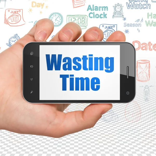 Time concept: Hand Holding Smartphone with Wasting Time on display