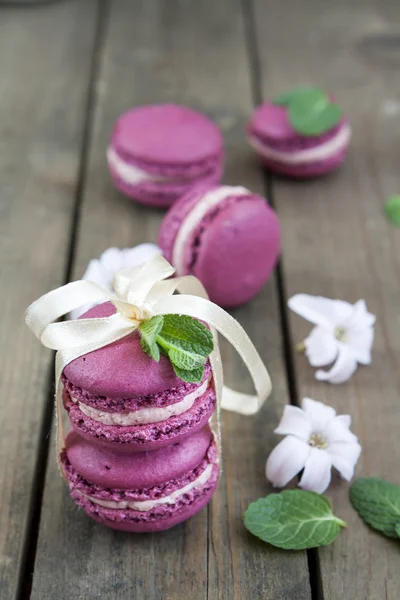 Sweet crimson french macaroons wiht hyacinth flowers and mint on dark wooden background