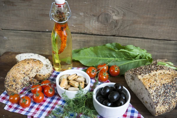 Black olives and mussels in ceramic bowls, fresh tomatoes, bread and bottle of olive oil with spices