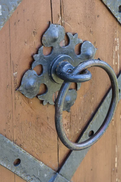 Door handle-knocker on the vintage metal dark grey door