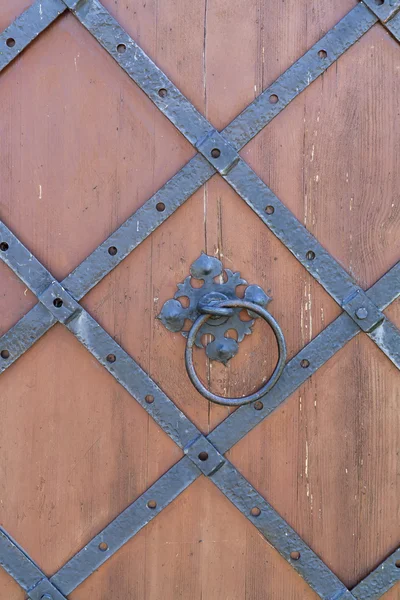 Door handle-knocker on the vintage metal dark grey door