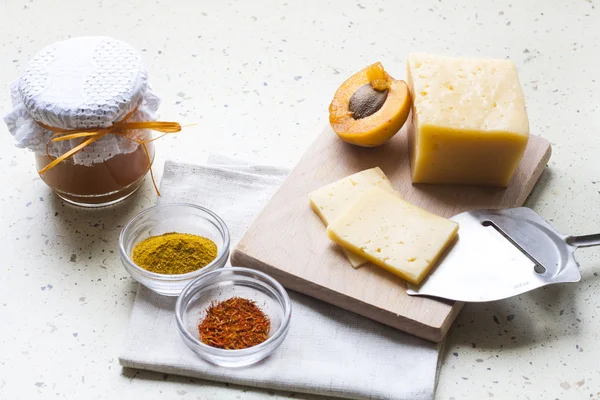 Solid sliced cheese with apricot curry in ceramic ware, spices and fresh apricots, selective focus