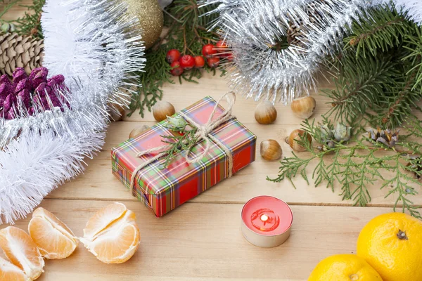 Christmas gift box and red candle with New Year's and Christmas decoration midst fruits and tinsel