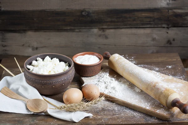 Rustic natural dairy products. Rustic natural dairy products cottage cheese, sour cream in clay dishes, eggs and ears of wheat on the old wooden background.