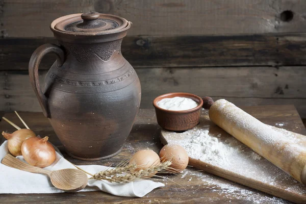 Rustic natural dairy products. Rustic natural dairy products sour cream in clay dishes, eggs and ears of wheat on the old wooden background.