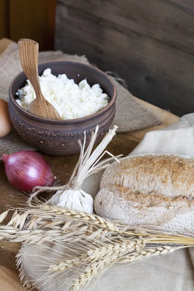 Rustic natural dairy products. Rustic natural dairy products cottage cheese and bread, eggs, onions and garlic of wheat on the old wooden background.