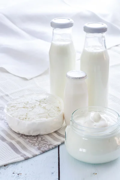 Dairy products. Milk in glass bottle, yogurt, sour milk cheese, sour cream with checkered napkin on light blue wooden table