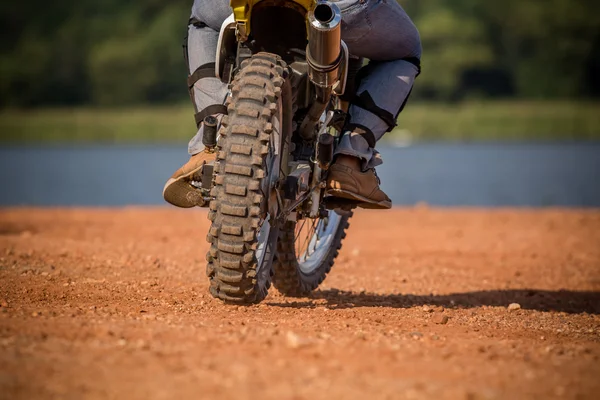 Man riding enduro motorcycle on dirt field