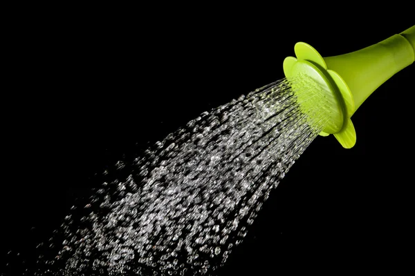 Green watering can pouring water with high speed shutter isolate