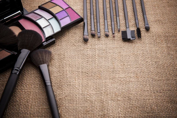 Eye shadow cosmetic and make up brush on brown textile texture u