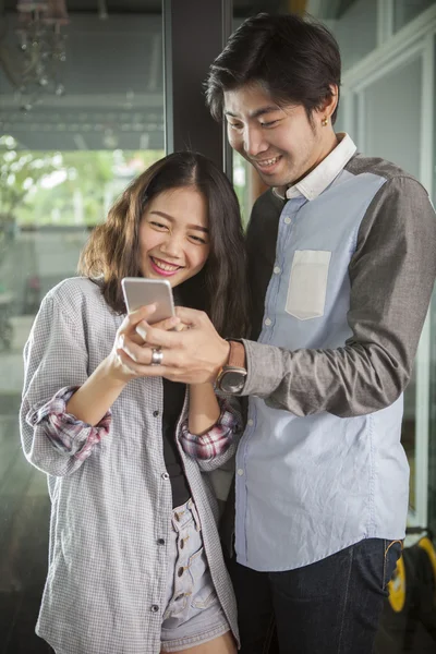 Asian younger man and woman watching on smart phone with happy f