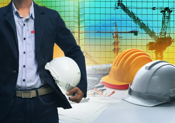 Engineering man standing with white safety helmet against buildi