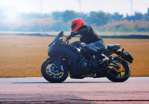 Young man riding motorcycle in asphalt road curve with with a mo