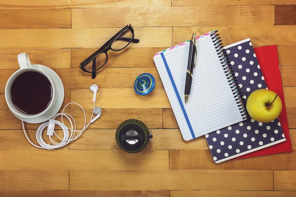 Notebooks, pen, glasses, apple on a wooden.