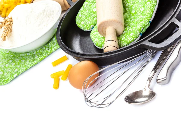 Kitchen utensils, eggs, flour for baking and frying pan.