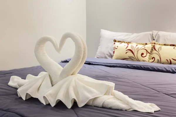 Towel folded in swan shape on bed sheet