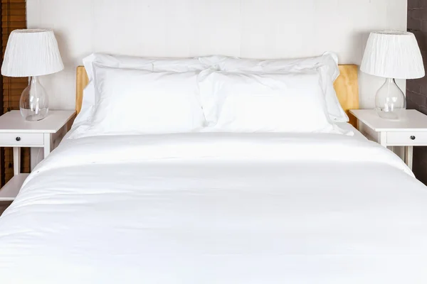 Two pillow on bedroom with white bed sheet and lamp