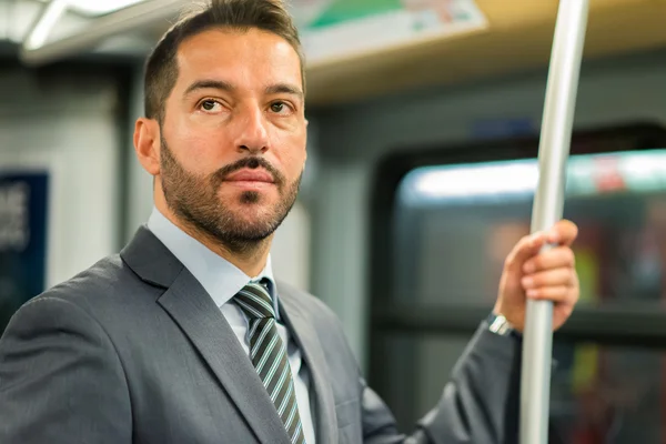 Businessman hanging to pole in train