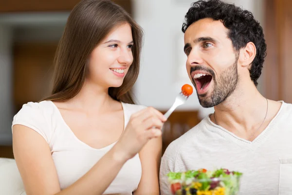 Couple eating salad in living room