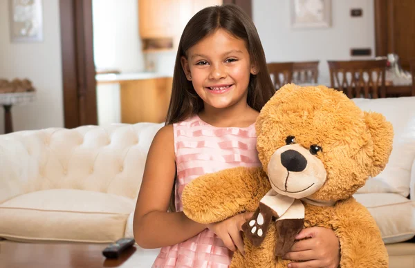 Girl holding a teddy bear at home