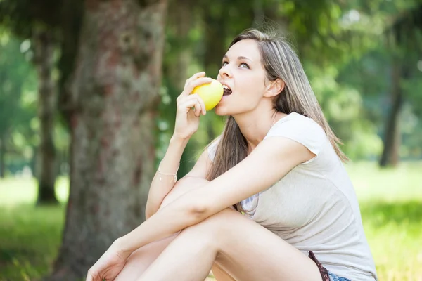 Woman eating apple in park