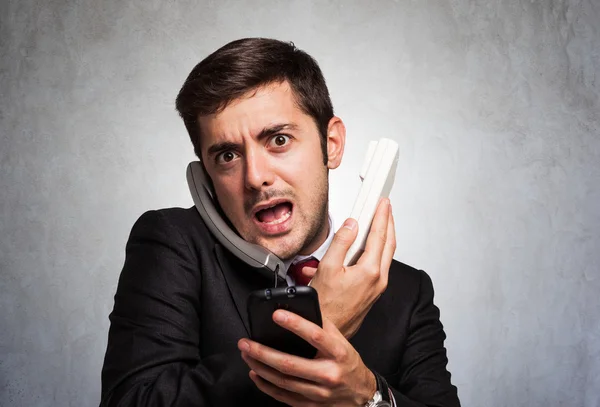 Stressed businessman talking on phones