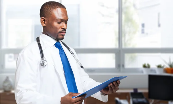 African doctor reading clipboard