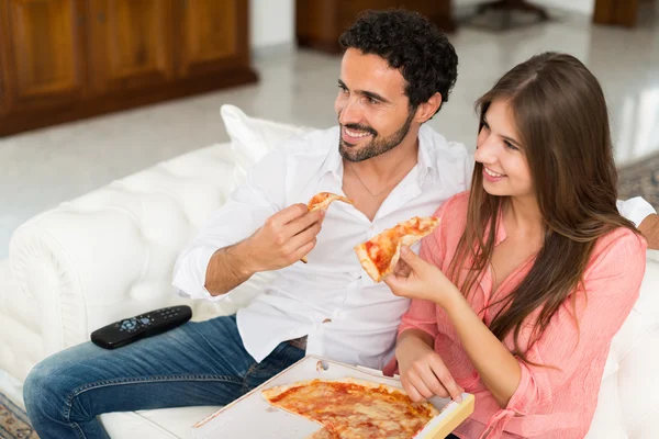 Couple watching tv and eating pizza