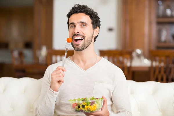 Man eating salad in apartment