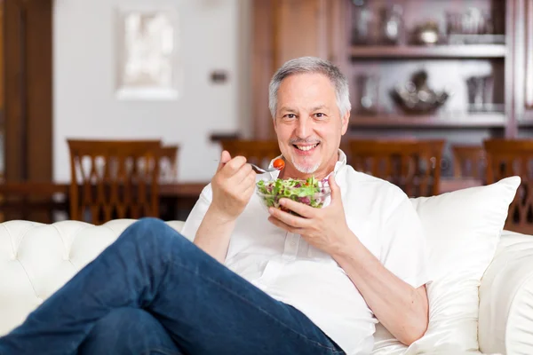 Man eating salad on sofa