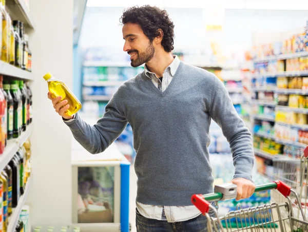 Man taking bottle of oil in supermarket