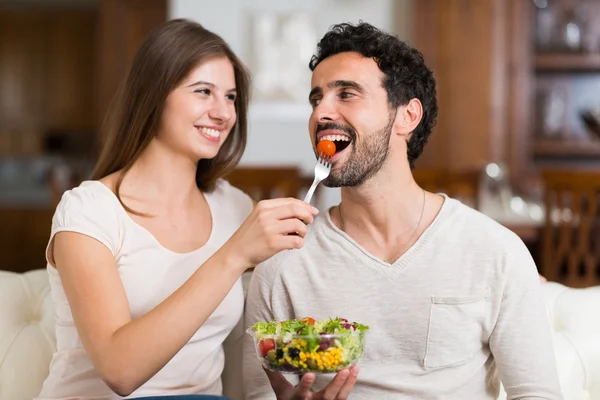 Couple eating salad in living room