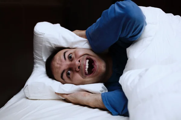 Man using pillow to cover ears