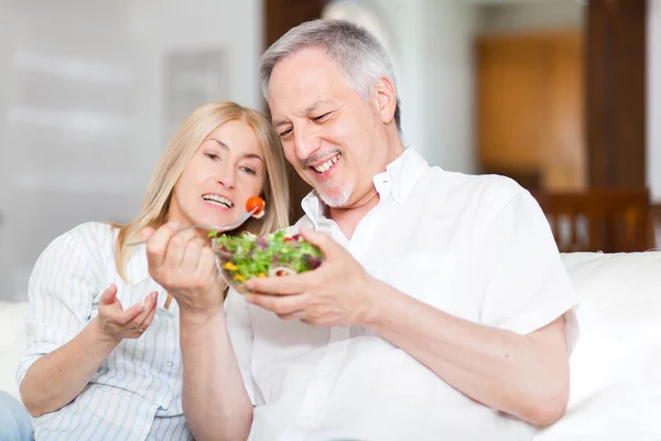 Couple eating salad in living room