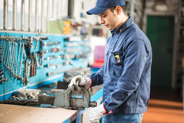 Worker securing metal plate in vise