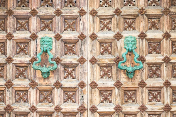 Ornate medieval door with two turquoise handles