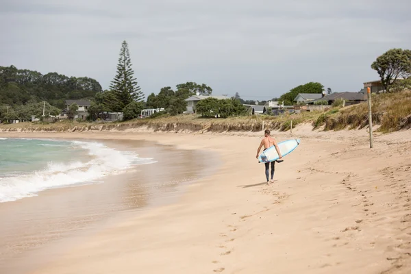 Surfer walking on the beach with his board