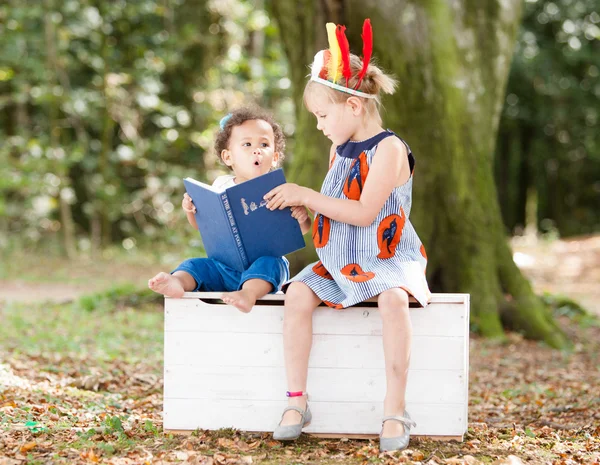 Children reading together in woods