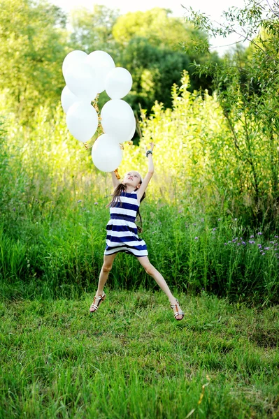 Kid girl with white balloons outside