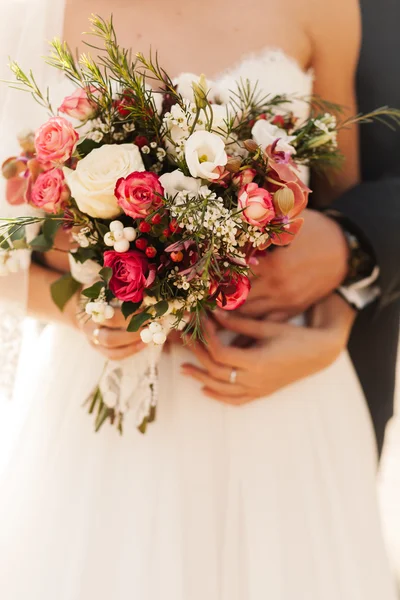 Groom hugging bride holding roses bouquet